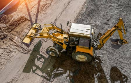 Aerial photo of backhoe driving on construction site 